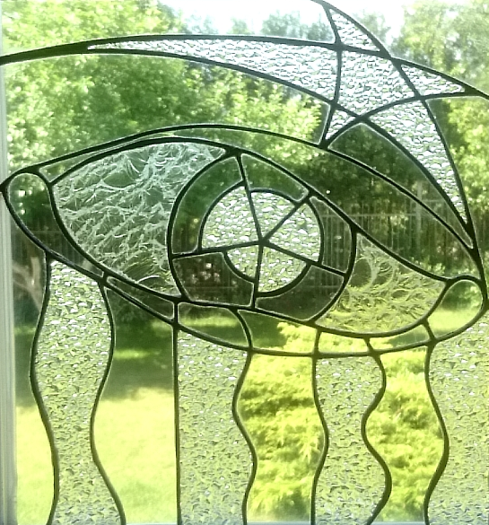 Skaidraus stiklo vitražas"Akis". Tiffany technika. Stačiakampė forma. Pavasarinės žalumos fone.